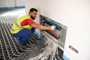 A man repairs a heating system in a room, focused on the equipment.